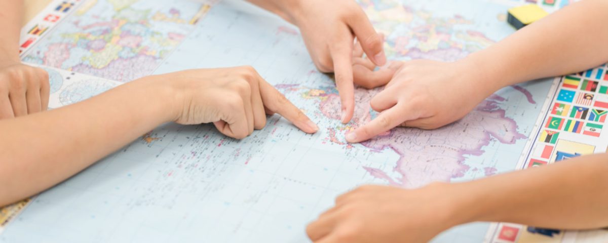 Otroci skupaj raziskujejo zemljevid sveta kot simbol globalnih priložnosti, ki jih prinaša znanje angleščine