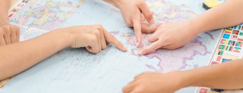 Otroci skupaj raziskujejo zemljevid sveta kot simbol globalnih priložnosti, ki jih prinaša znanje angleščine
